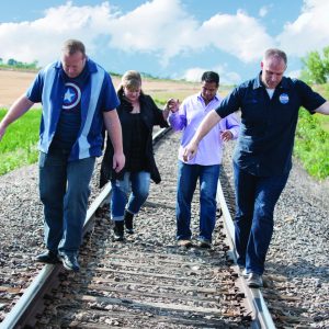 Four members of the band LMNOP walk along a railroad track