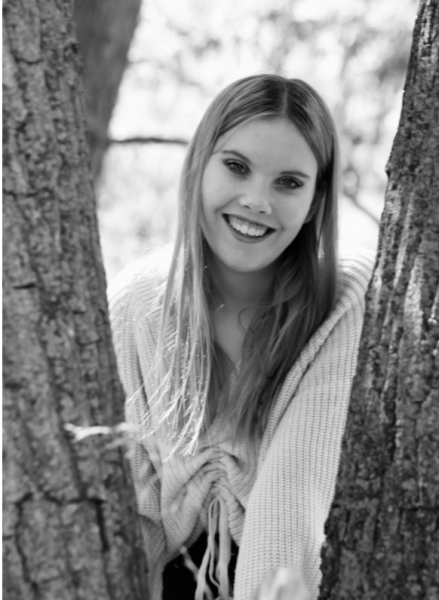 Olivia Calzaretta promotional headshot smiling between two tree trunks