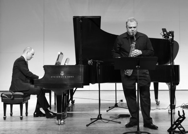 Black and White photo of Russell Hirshfield playing piano behind Dan Goble playing the saxophone