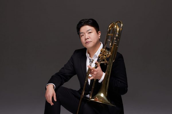 2025 Guest artist Minhwan Lee pictured in a suit with his trombone